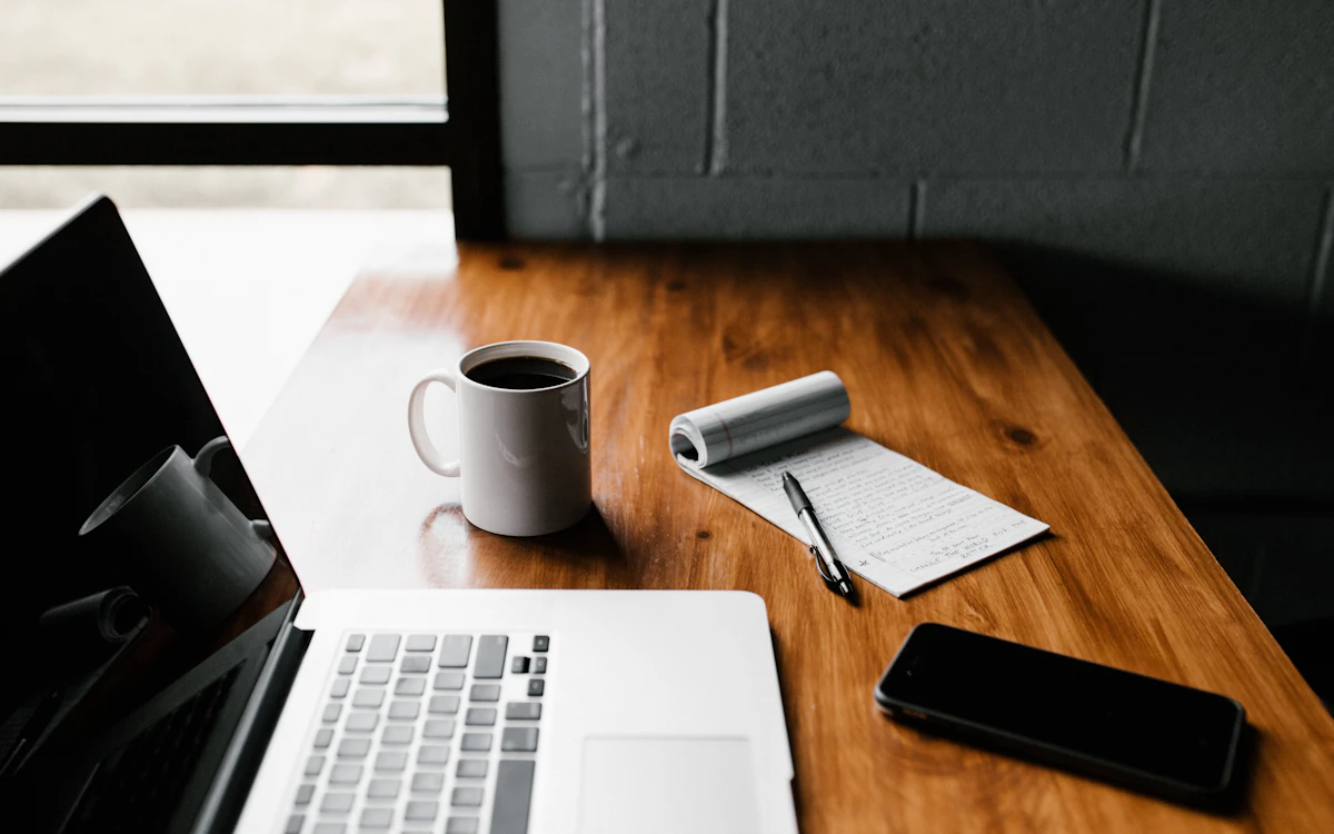 Clean wooden workspace with an open notebook, laptop, and written notes